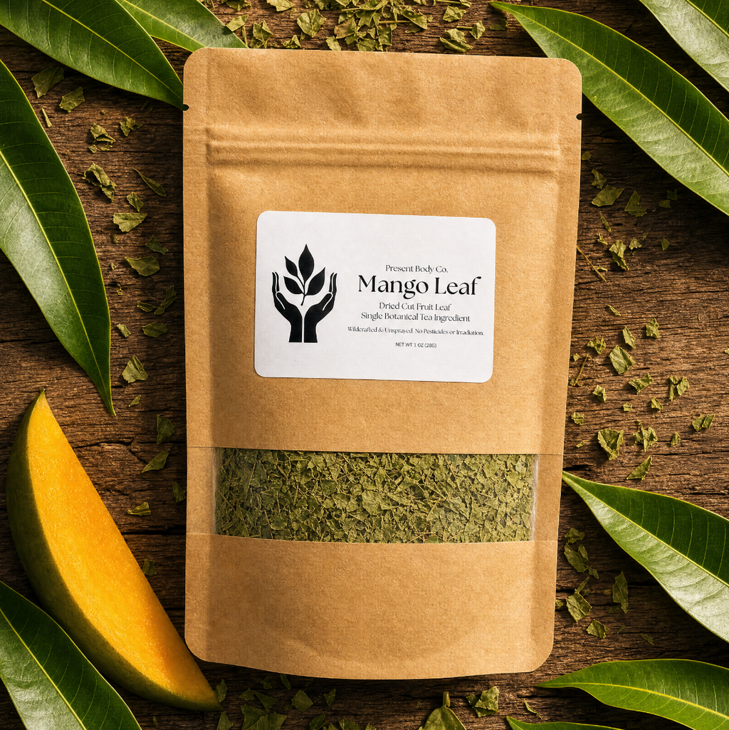 A kraft paper stand-up pouch labeled Mango Leaf, surrounded by fresh green mango leaves and dried leaf pieces on a rustic wooden surface.