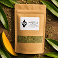 A kraft paper stand-up pouch labeled Mango Leaf, surrounded by fresh green mango leaves and dried leaf pieces on a rustic wooden surface.