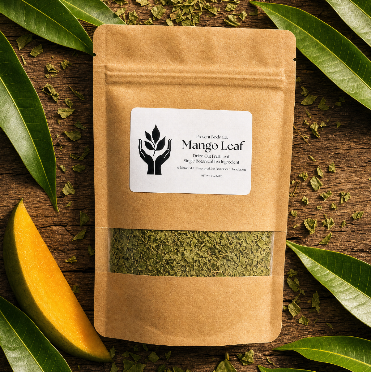 A kraft paper stand-up pouch labeled Mango Leaf, surrounded by fresh green mango leaves and dried leaf pieces on a rustic wooden surface.