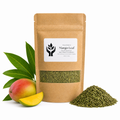A kraft paper stand-up pouch of Mango Leaf by Present Body Co., shown on a white background with a whole mango, a mango slice, green leaves, and a pile of dried green leaf material.