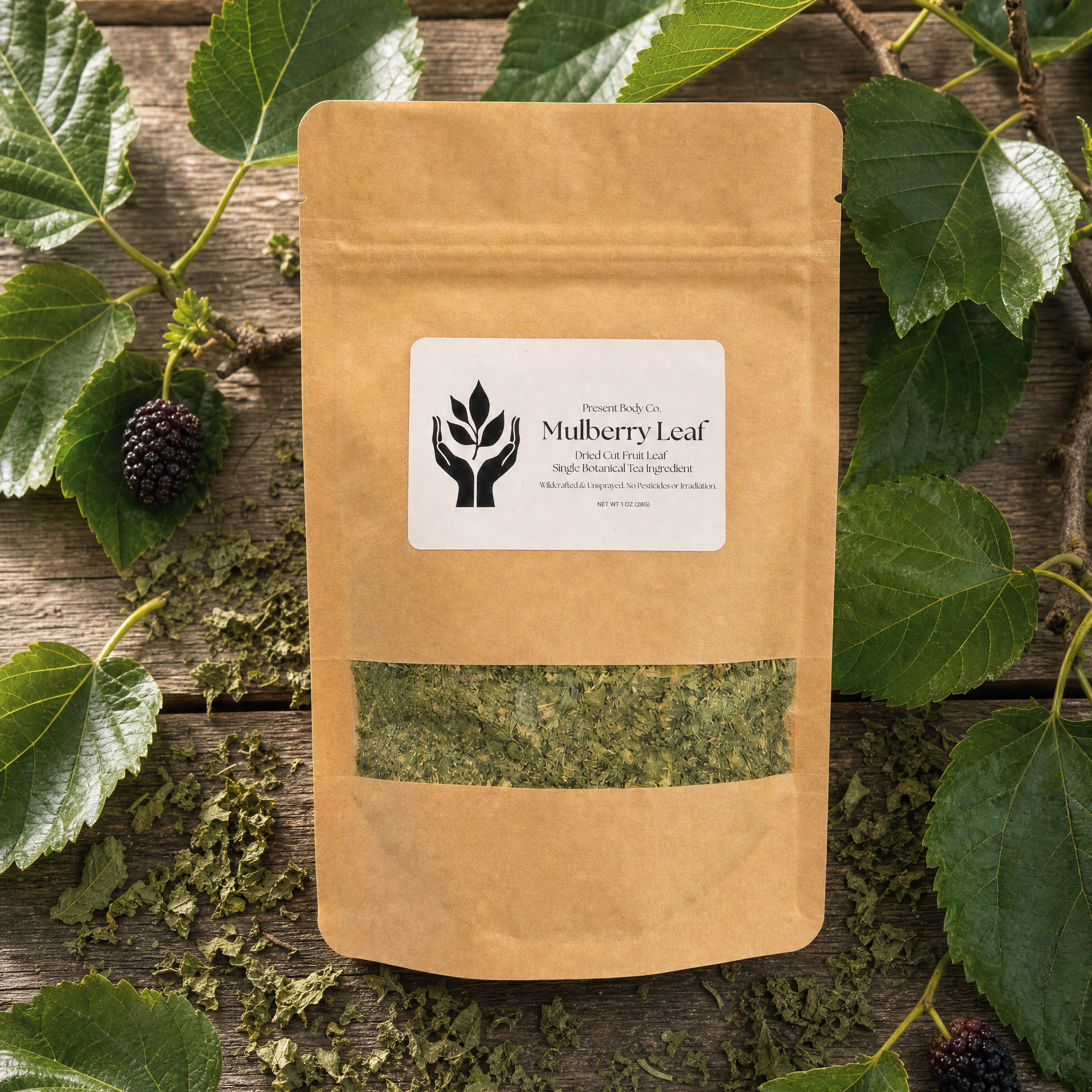 A kraft paper stand-up pouch labeled 'Mulberry Leaf' with a clear window showing dried green leaves, arranged on a rustic wooden surface with fresh green leaves and berries around it.