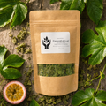 A kraft paper stand-up pouch labeled 'Passionfruit Leaf' with a clear window showing dried green leaves inside, styled on a rustic wood surface with green leaves and a halved passionfruit around it.