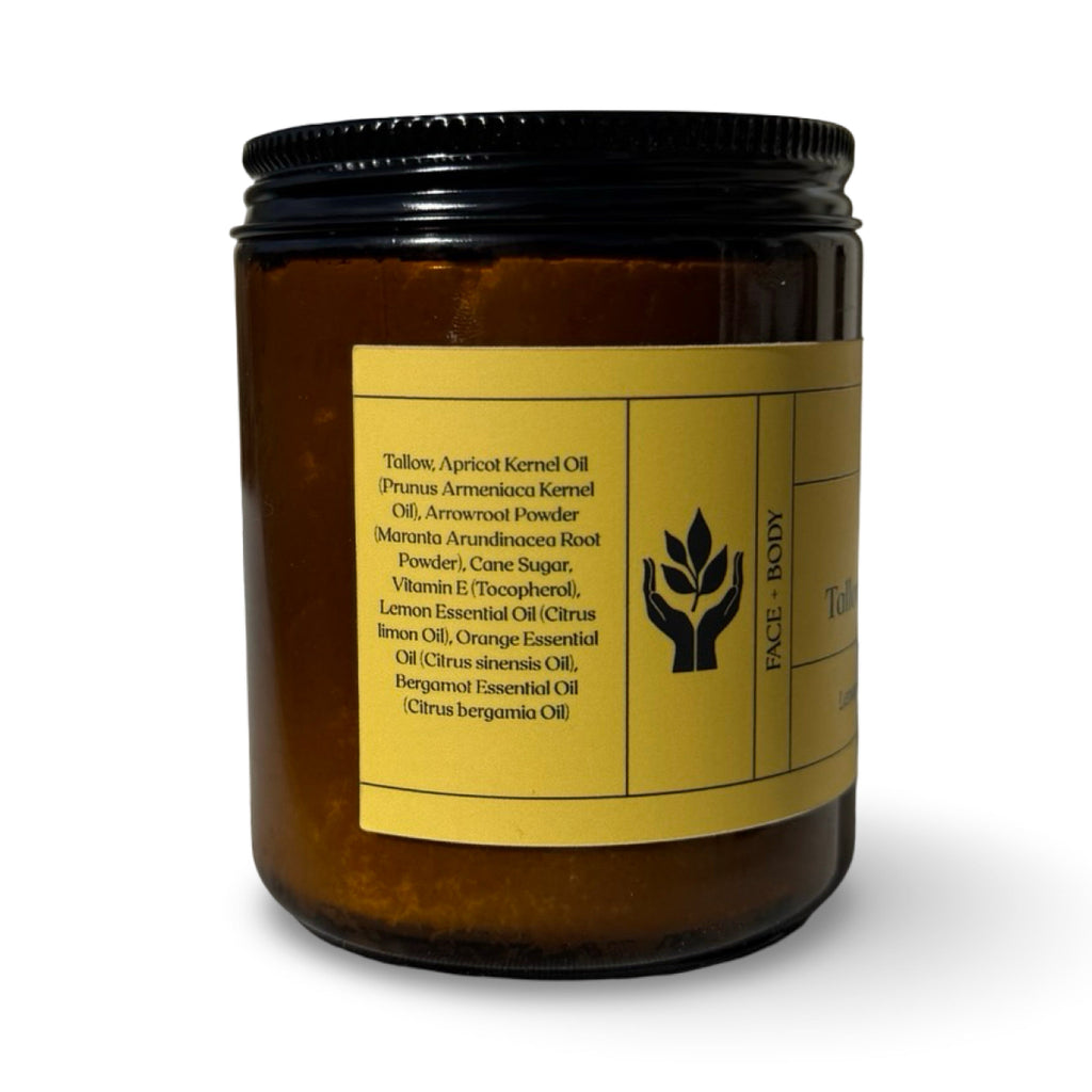 An amber glass jar  with a black metal lid and a yellow label, shown on a white background. The label lists ingredients including tallow, apricot kernel oil, and essential oils.