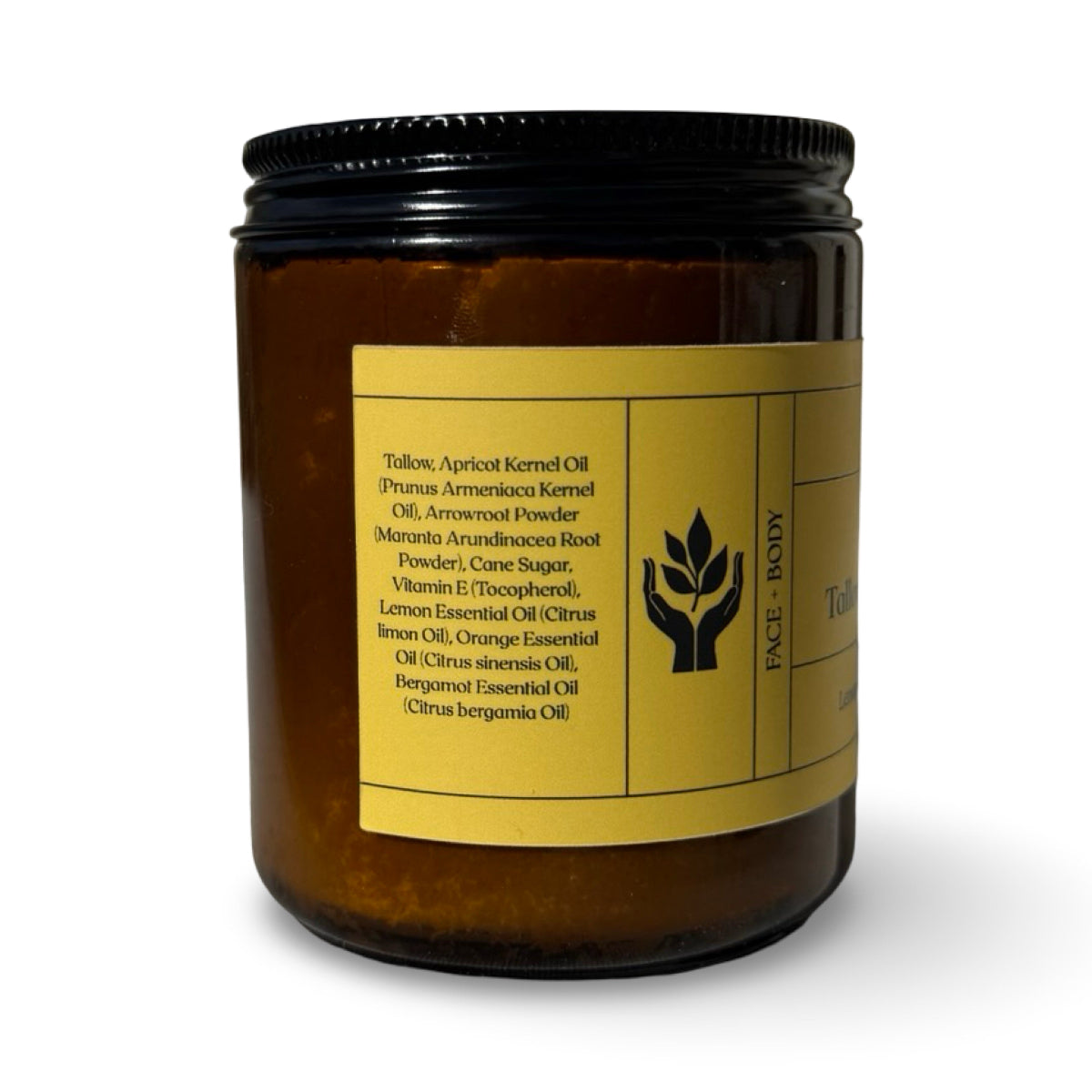 An amber glass jar  with a black metal lid and a yellow label, shown on a white background. The label lists ingredients including tallow, apricot kernel oil, and essential oils.