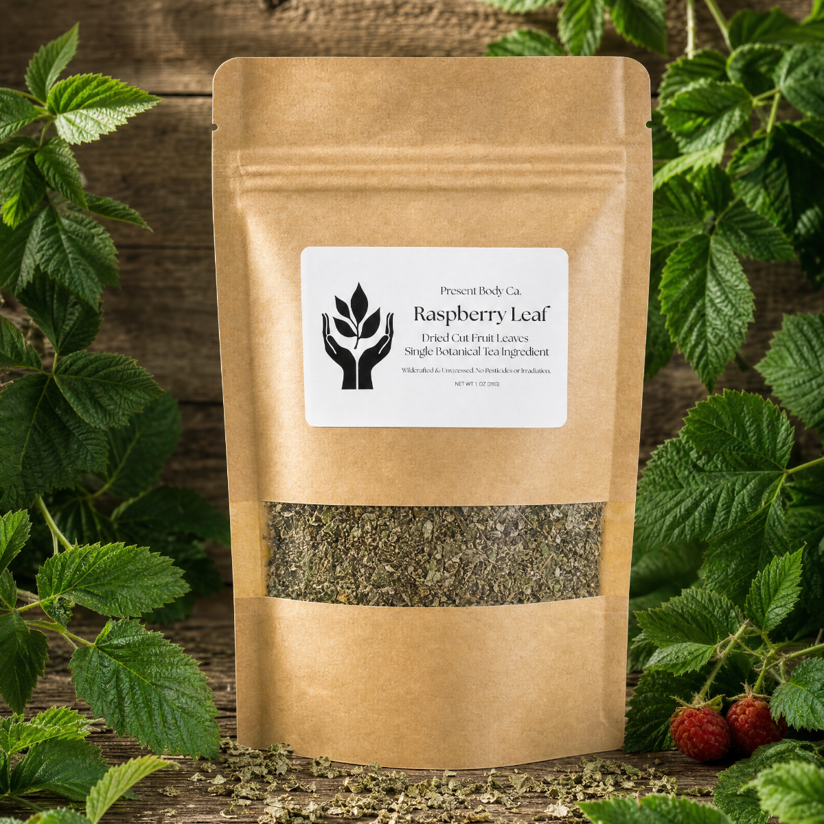 A kraft paper stand-up pouch labeled 'Raspberry Leaf' by PowerBody Co., surrounded by fresh green leaves and a few red raspberries on a rustic wooden surface.