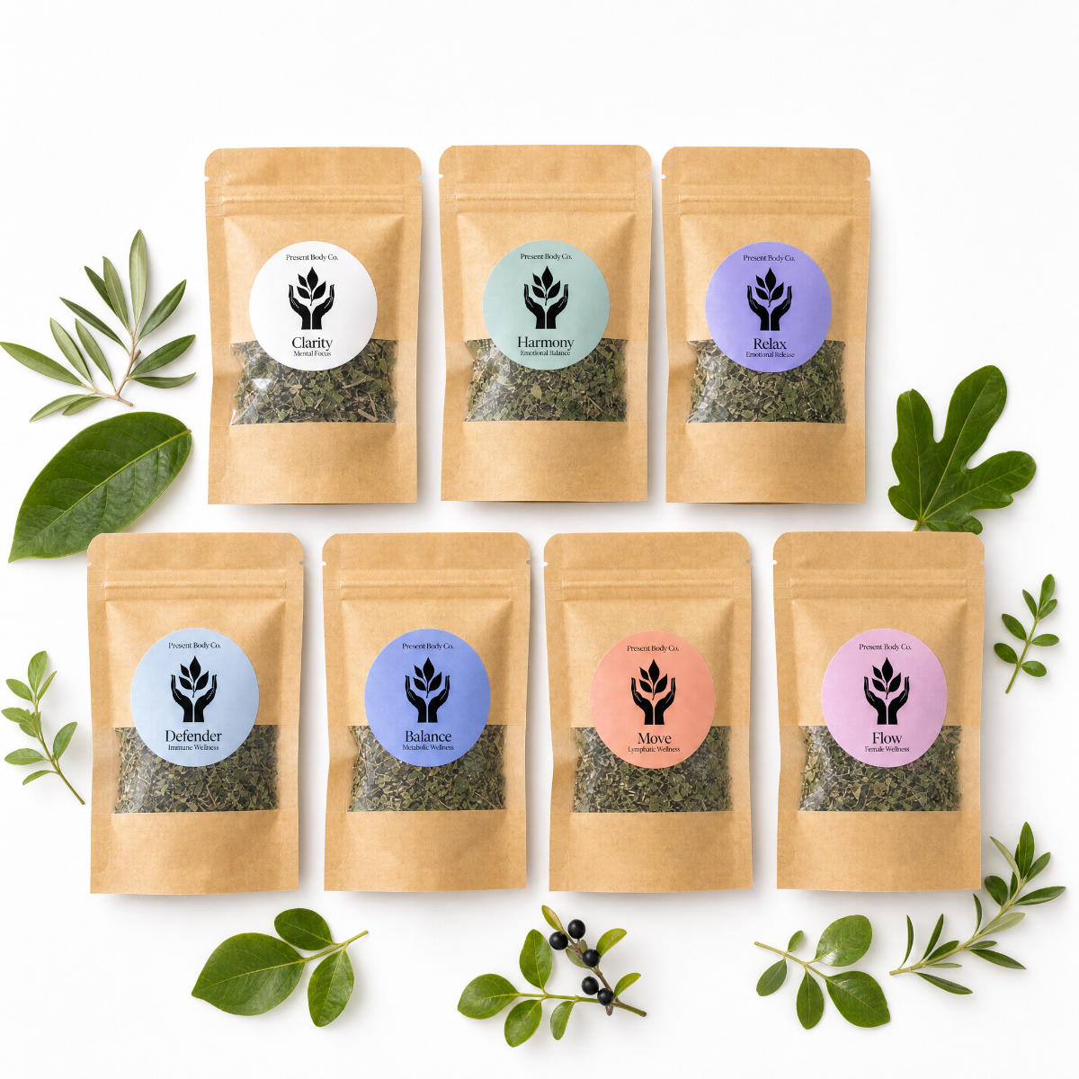 Seven kraft paper stand-up pouches of Present Body Co. tea blends arranged in two rows on a white background, surrounded by green leaves and small botanical sprigs.