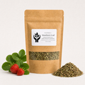 A kraft paper stand-up pouch labeled 'Strawberry Leaf' with a clear window showing dried green leaves inside, styled with fresh strawberry leaves and two strawberries on the left and a small pile of the dried leaves on the right, against a clean white background.