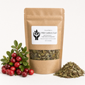 A kraft paper stand-up pouch labeled Present Root Co. Wild Cranberry Leaf, shown with a cluster of red cranberries on the left and a small pile of dried green cranberry leaves on the right against a clean white background.